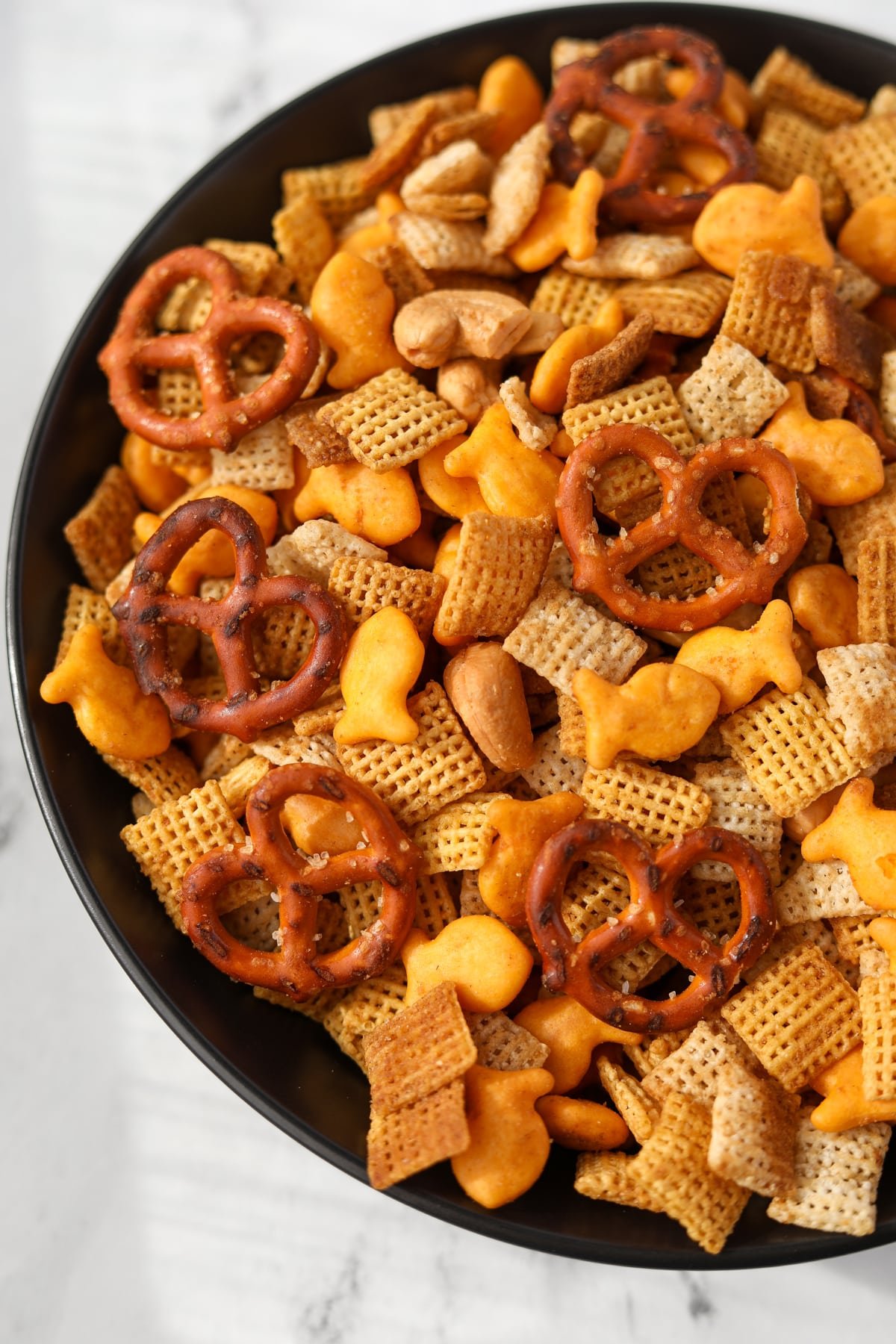 A black bowl with homemade chex mix in it.