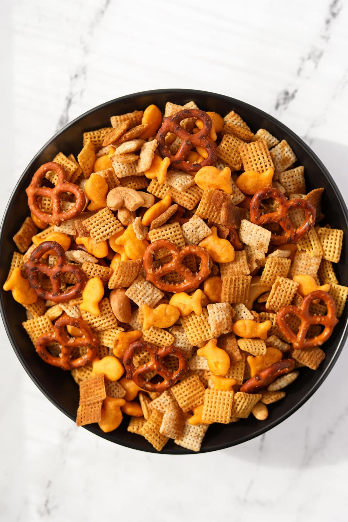 A bowl of homemade snack mix with pretzels, crackers, cereal, and nuts.