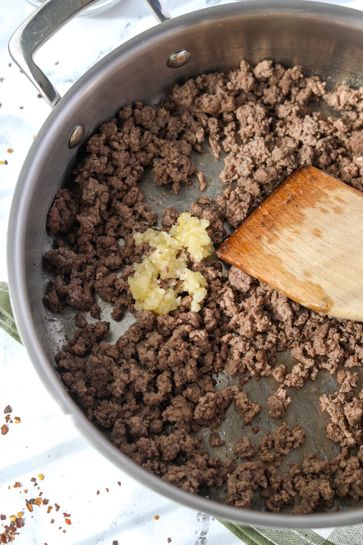 Adding garlic to a skillet with ground beef.