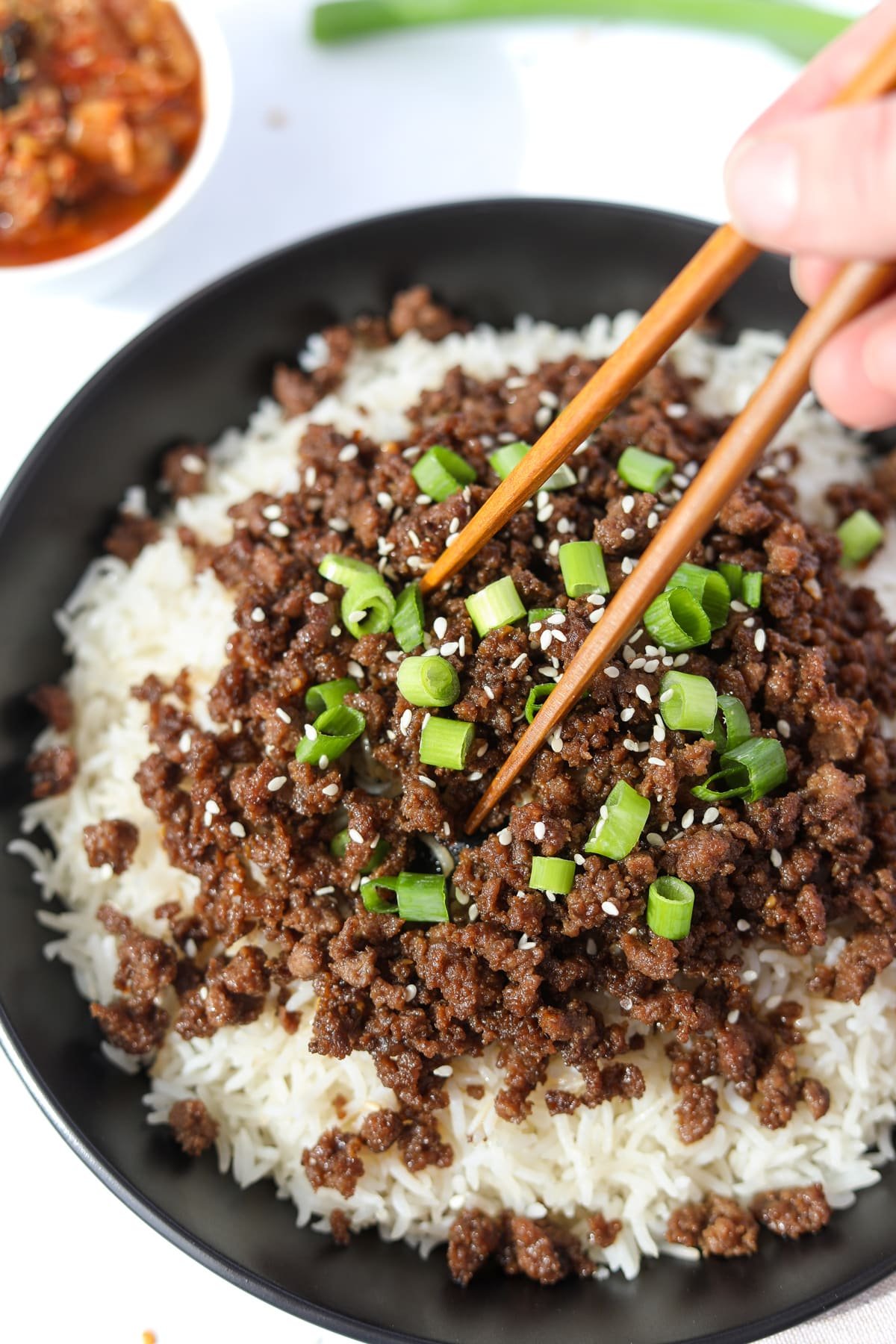 Using chopsticks to take a portion of rice and beef bowls.