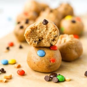Two cookie dough balls stacked on top of each other, with a bite taken out of the top one.