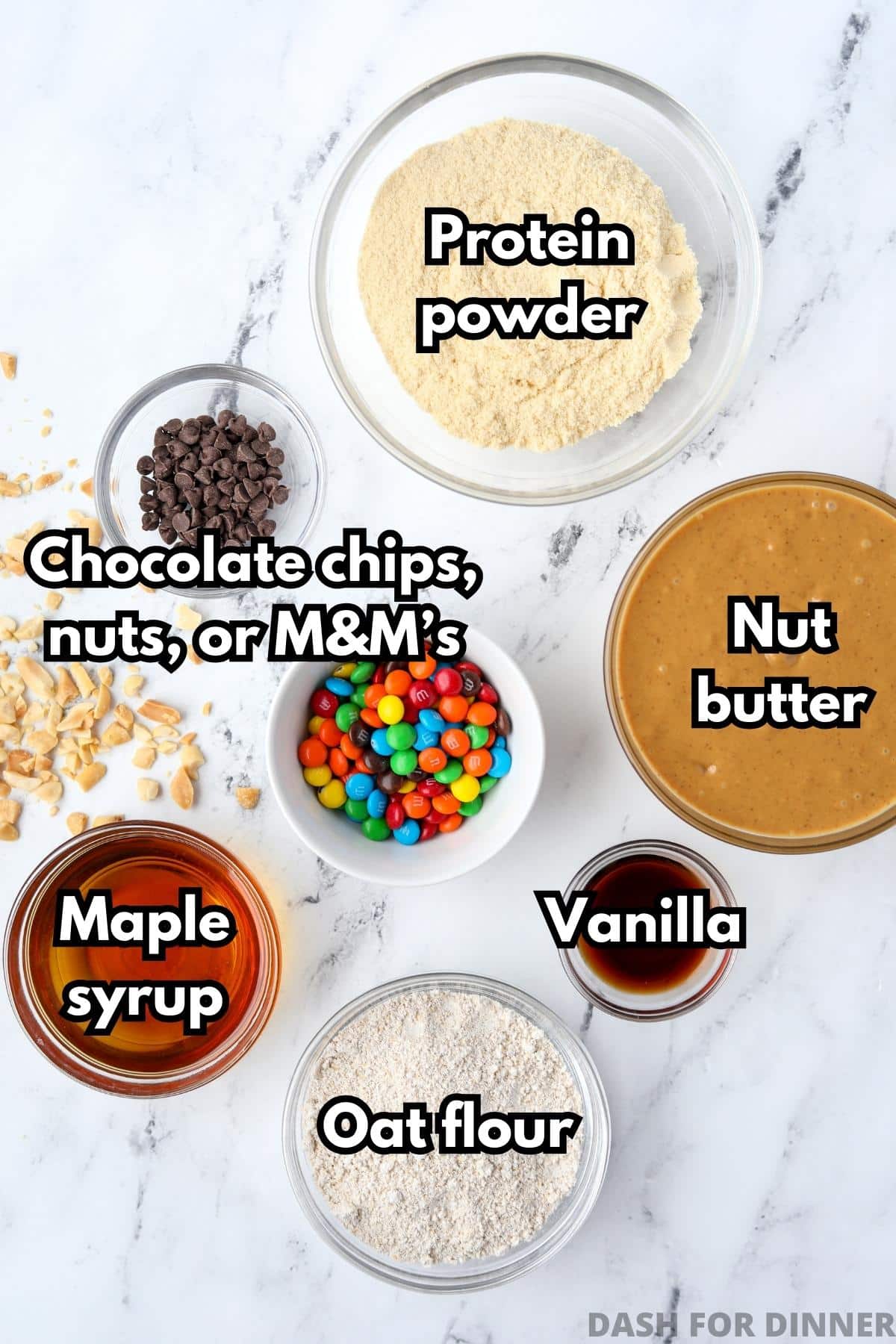 The ingredients needed to make protein cookie dough: nut butter, protein powder, mix-ins, maple syrup, oat flour, and vanilla.