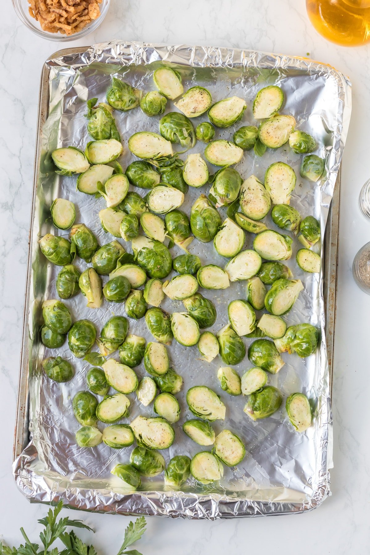 Sliced brussels sprouts laying on a foil-lined tray.
