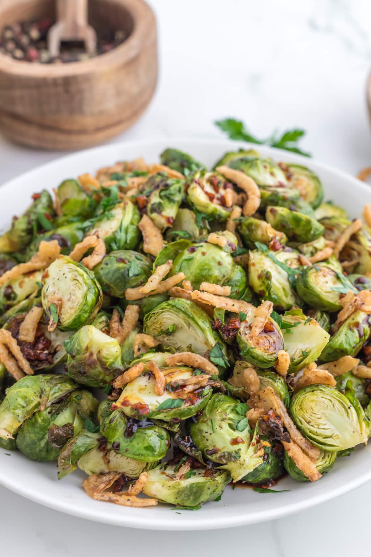A large platter filled with roasted brussels sprouts and topped with crispy fried onions.