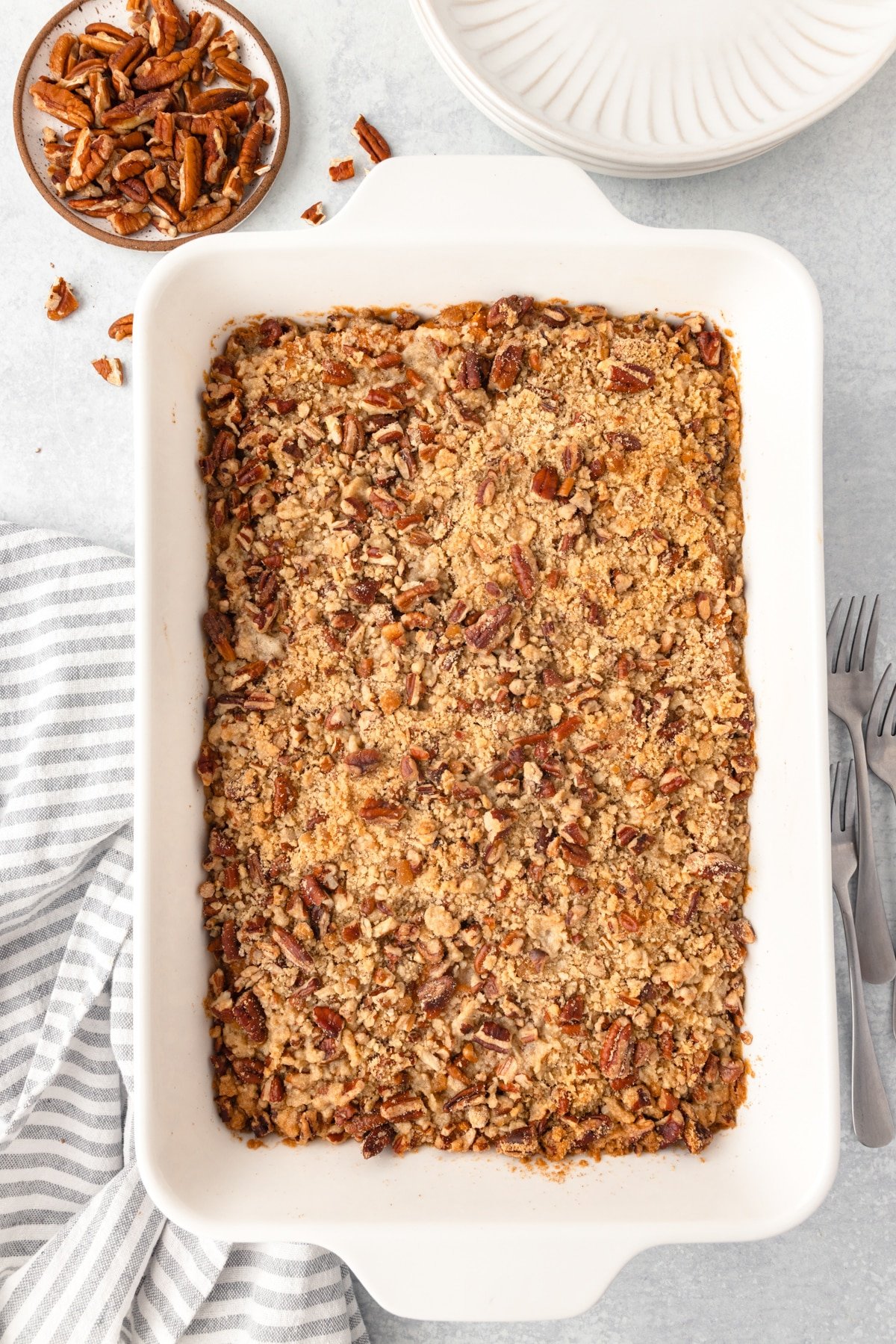 Sweet potato casserole in a large white baking dish, topped with pecans.