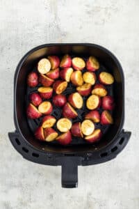An air fryer basket filled with baby potatoes.
