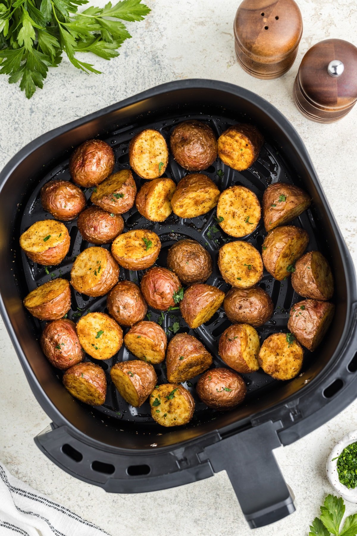 An air fryer basket filled with roasted baby red potatoes.