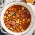 A large pot filled with ground beef stew with sliced sausages.