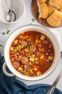 A pot filled with cowboy stew, with bread on the side.