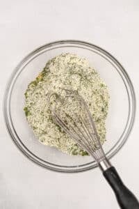 Whisking together herbs and buttermilk powder in a bowl.