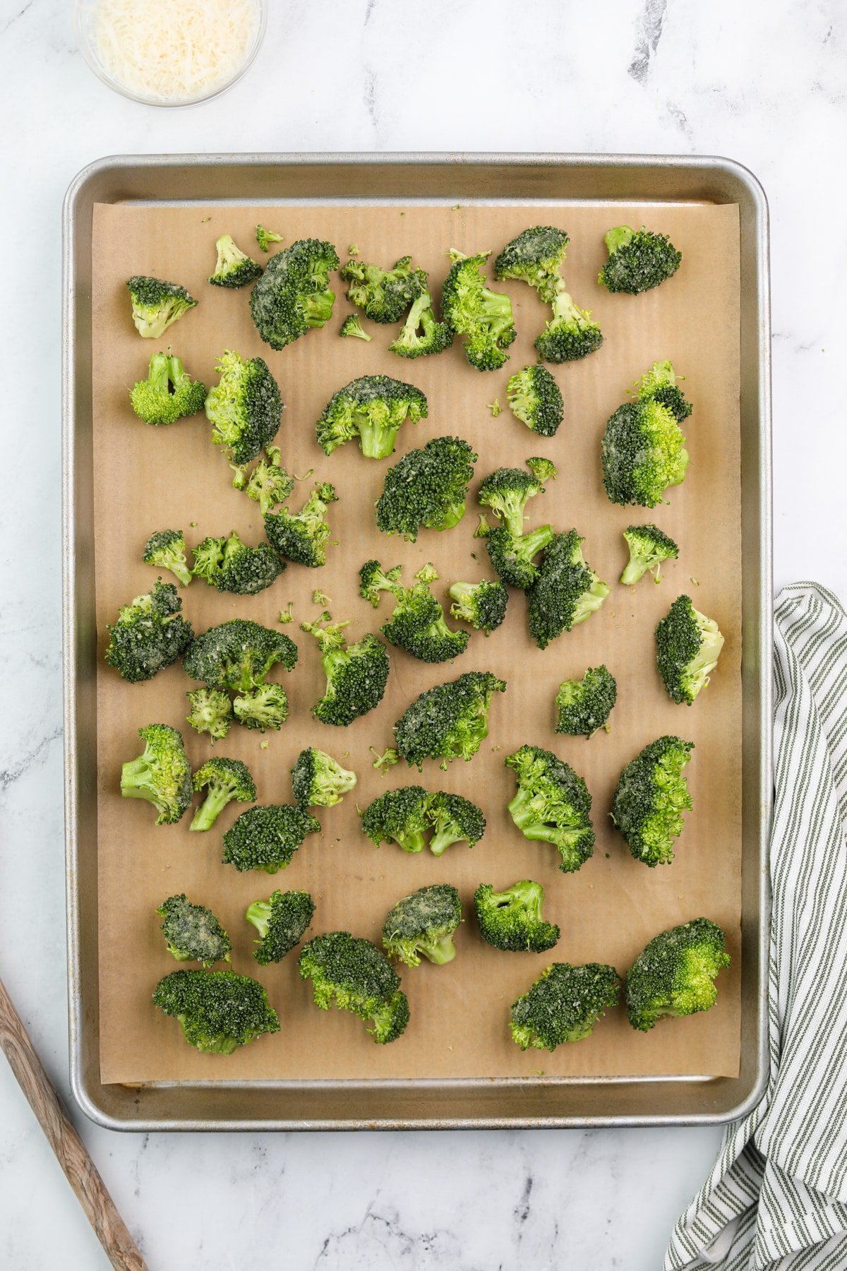 Broccoli florets spread onto a lined baking dish.