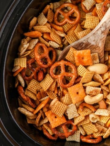 A slow cooker or crock pot insert filled with lightly browned Chex Mix.