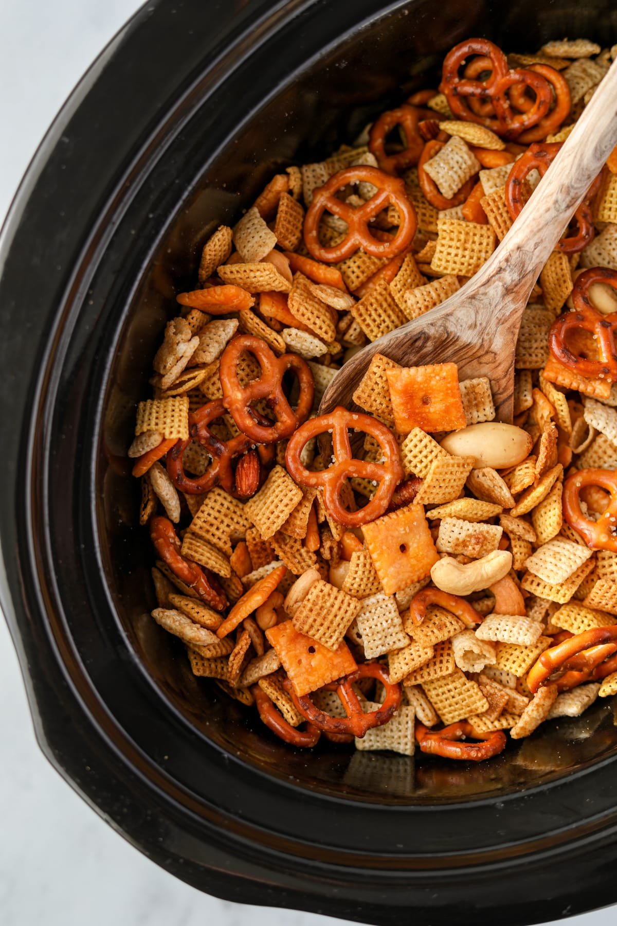 A slow cooker with Chex Mix inside.