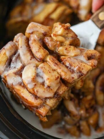 Taking a portion of crock pot cinnamon rolls from a slow cooker.