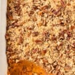 A baking dish filled with sweet potato casserole and topped with a pecan streusel.