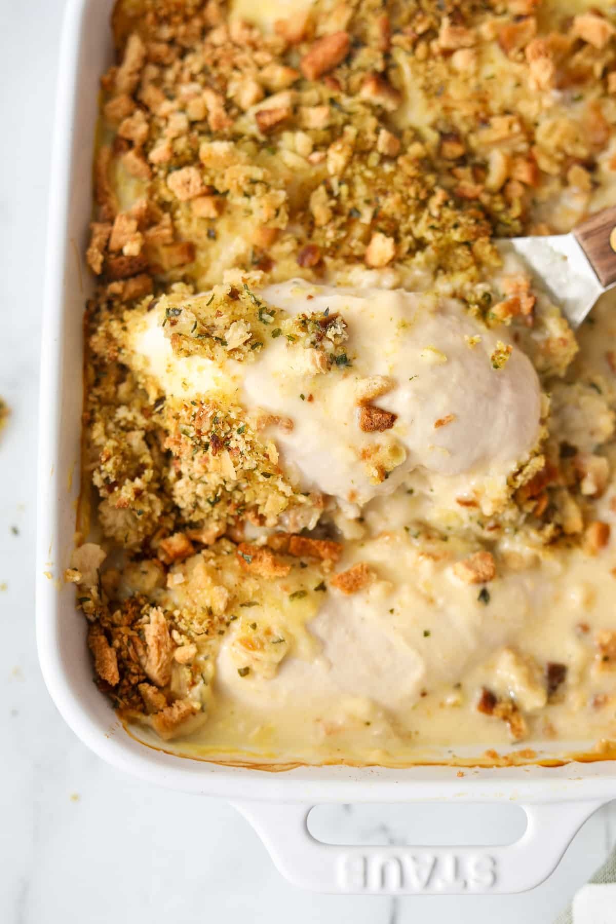 Lifting a chicken breast from a baking dish.