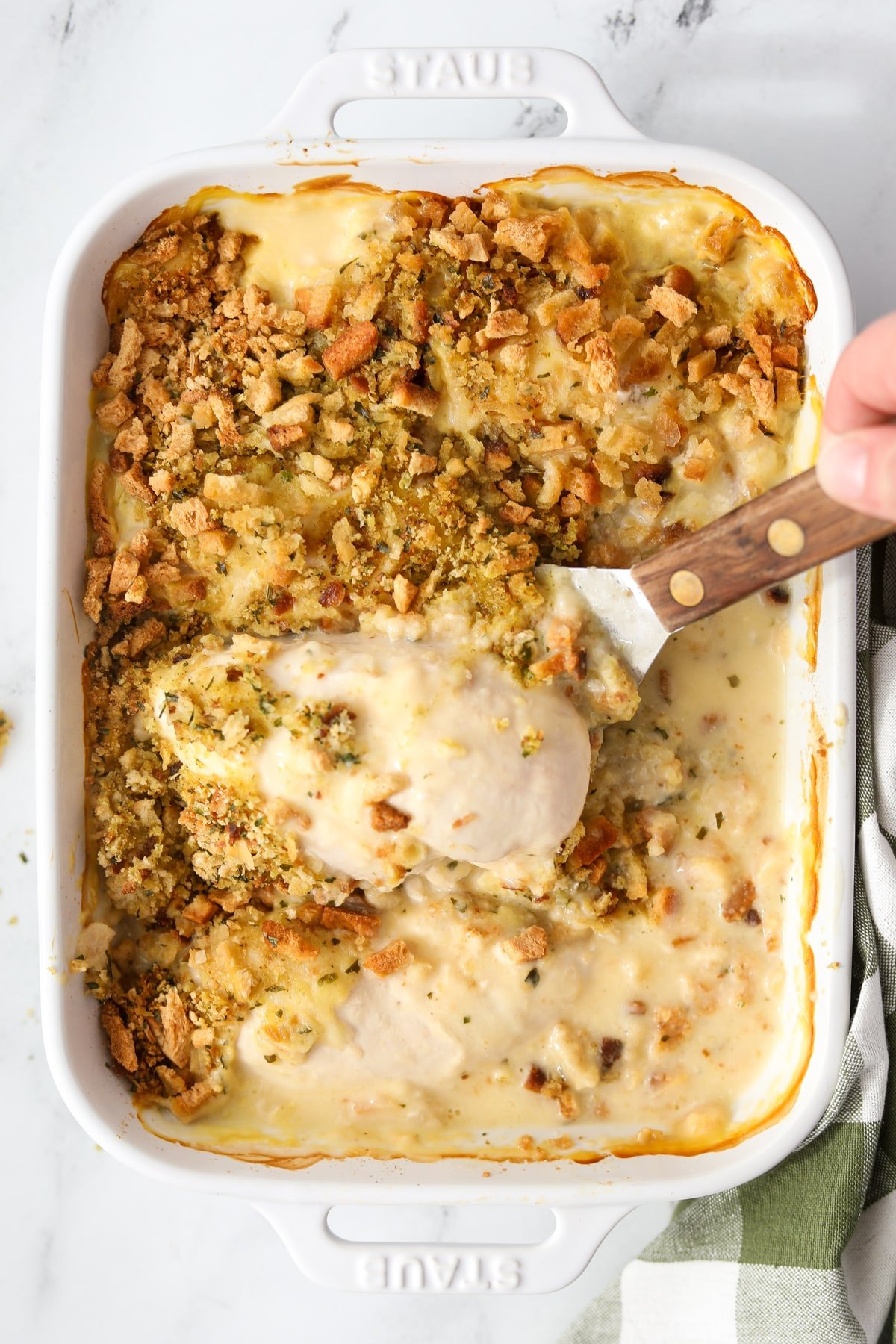 Lifting chicken and stuffing from a casserole dish.