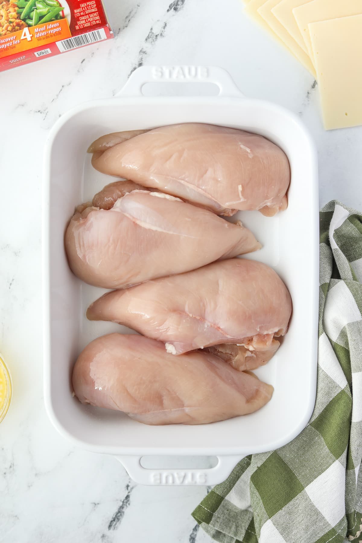 A baking dish with 4 chicken breasts in it.