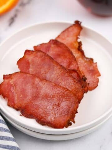 A small plate with four crispy slices of back bacon.