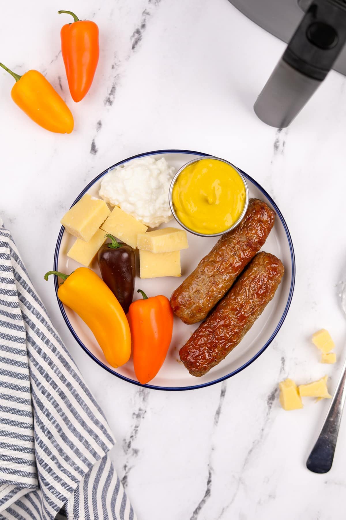 A plate with veggies, cottage cheese, mustard, and chicken sausages.