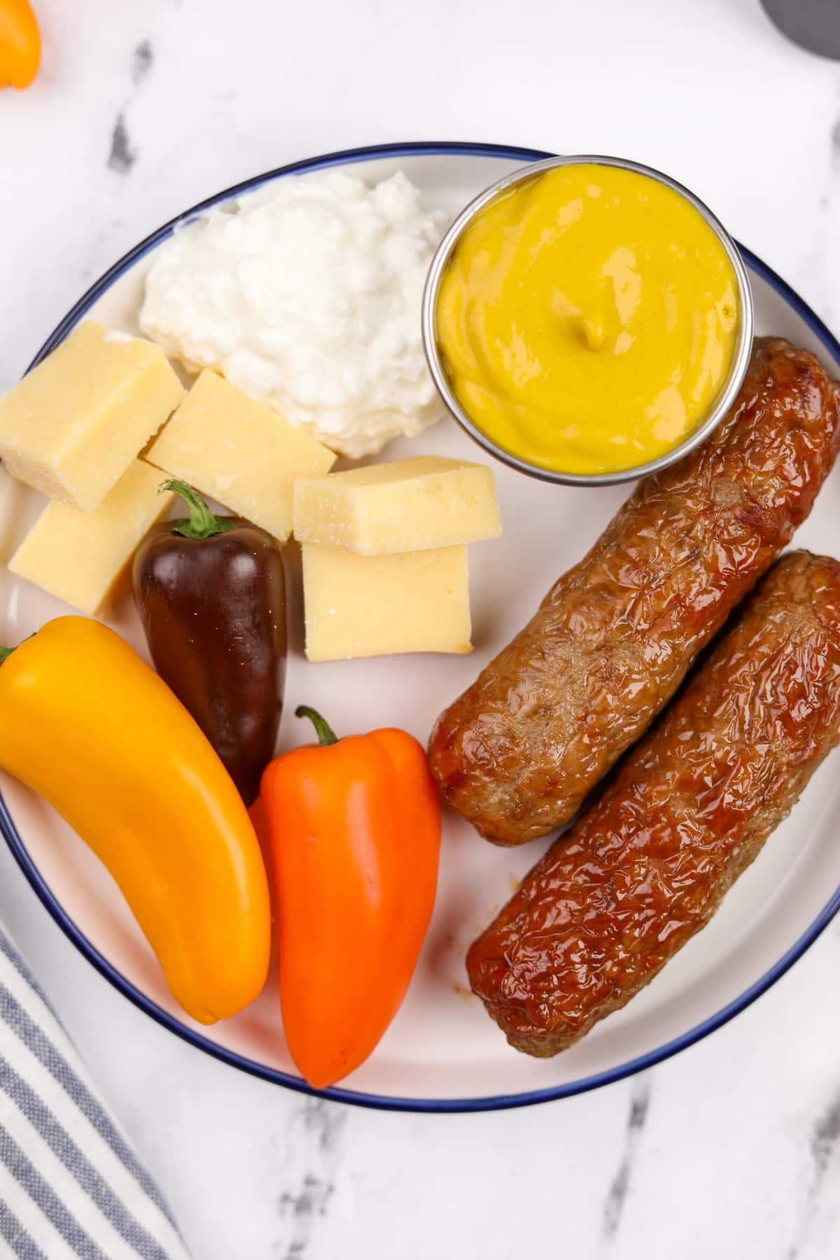 A plate filled with veggies, cheese, and chicken sausages.