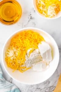 A bowl filled with cream cheese, cheese, and ranch seasoning. A small cup of beer is in the top left corner.
