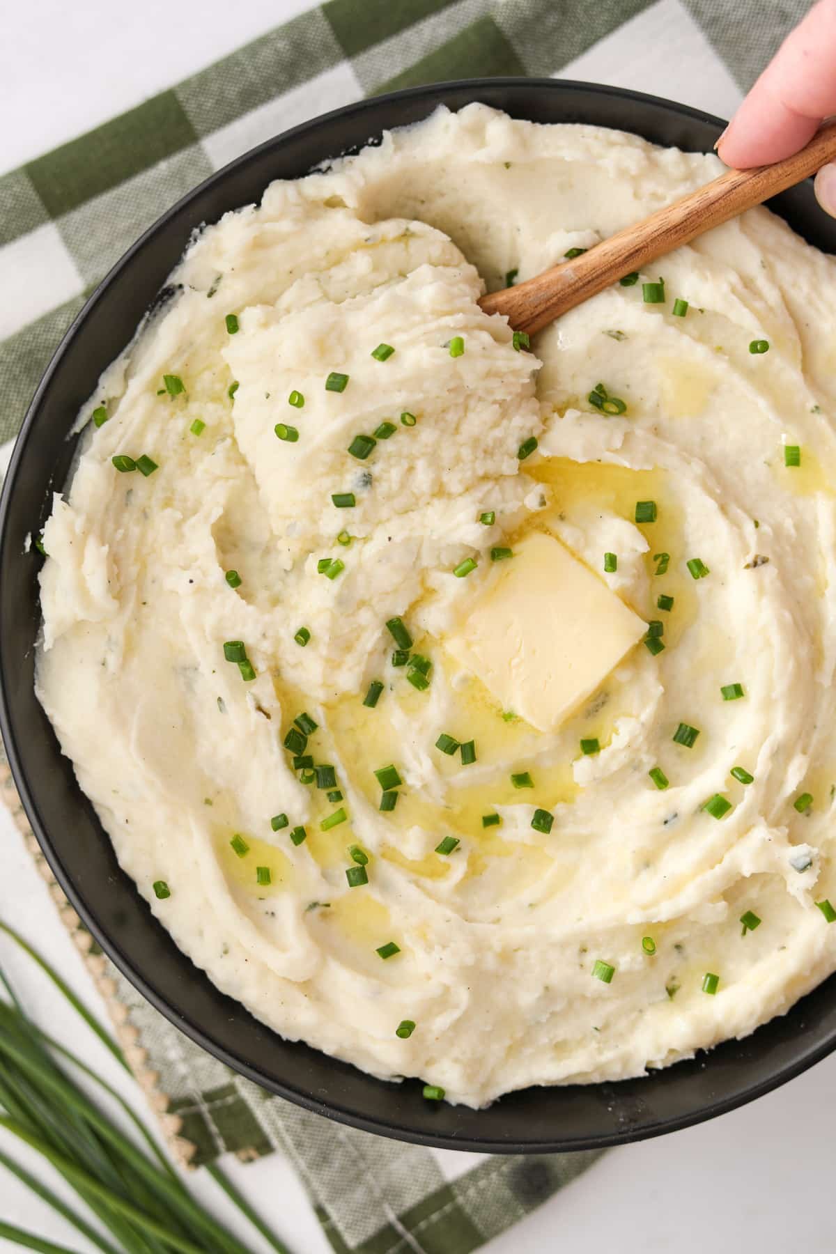A bowl of mashed potatoes topped with chopped chives.