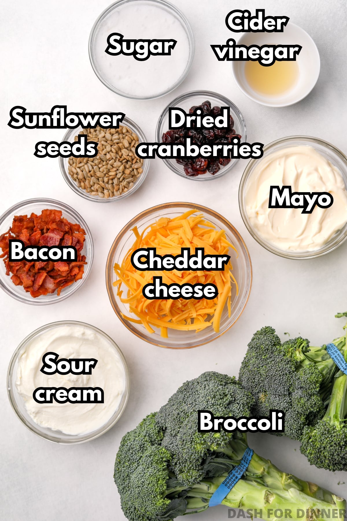 The ingredients needed to make broccoli salad, including cheddar cheese, bacon, sour cream, and mayo.