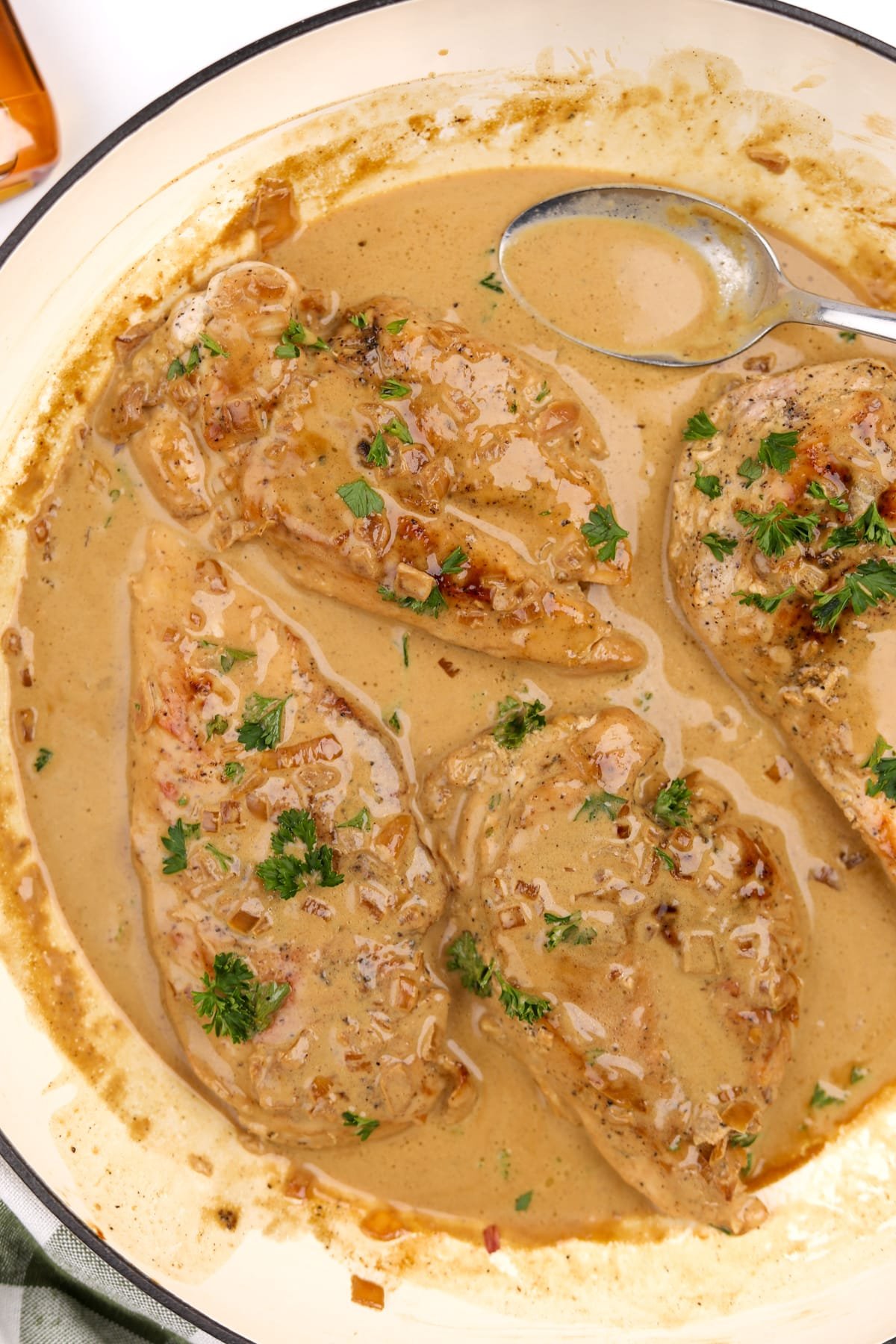 A skillet with chicken breasts covered in a creamy sauce.
