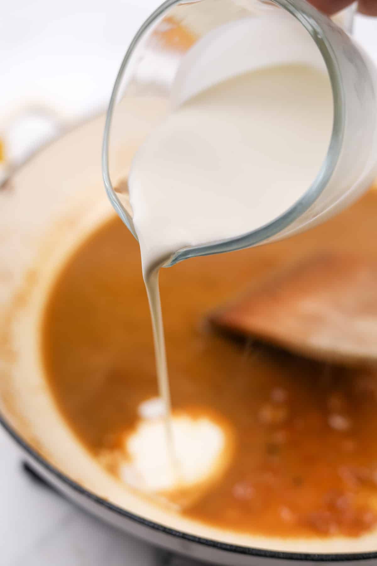 Pouring heavy cream into a skillet.