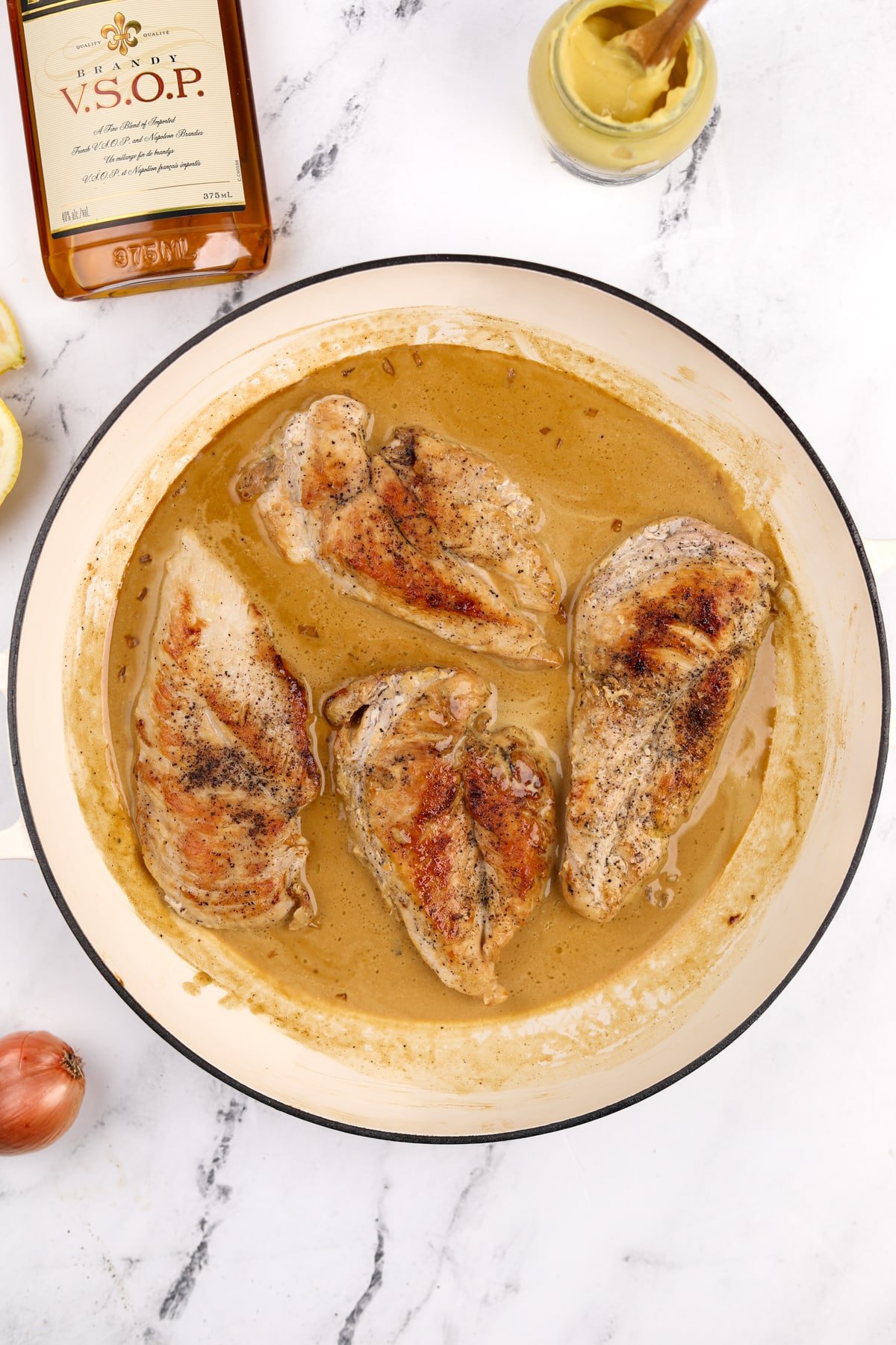 A skillet with a creamy pan sauce and cooked chicken breasts.
