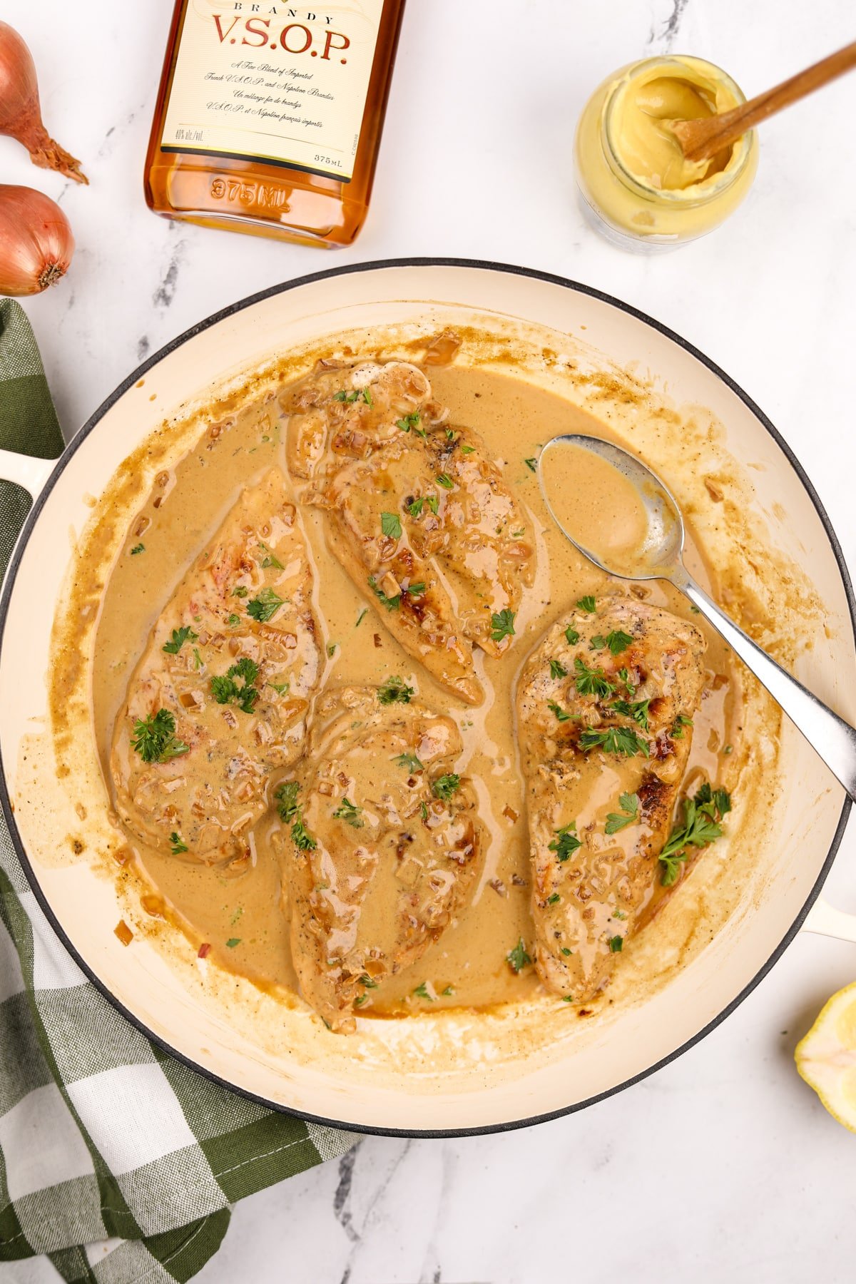 A skillet filled with cooked chicken breasts and a creamy pan sauce.