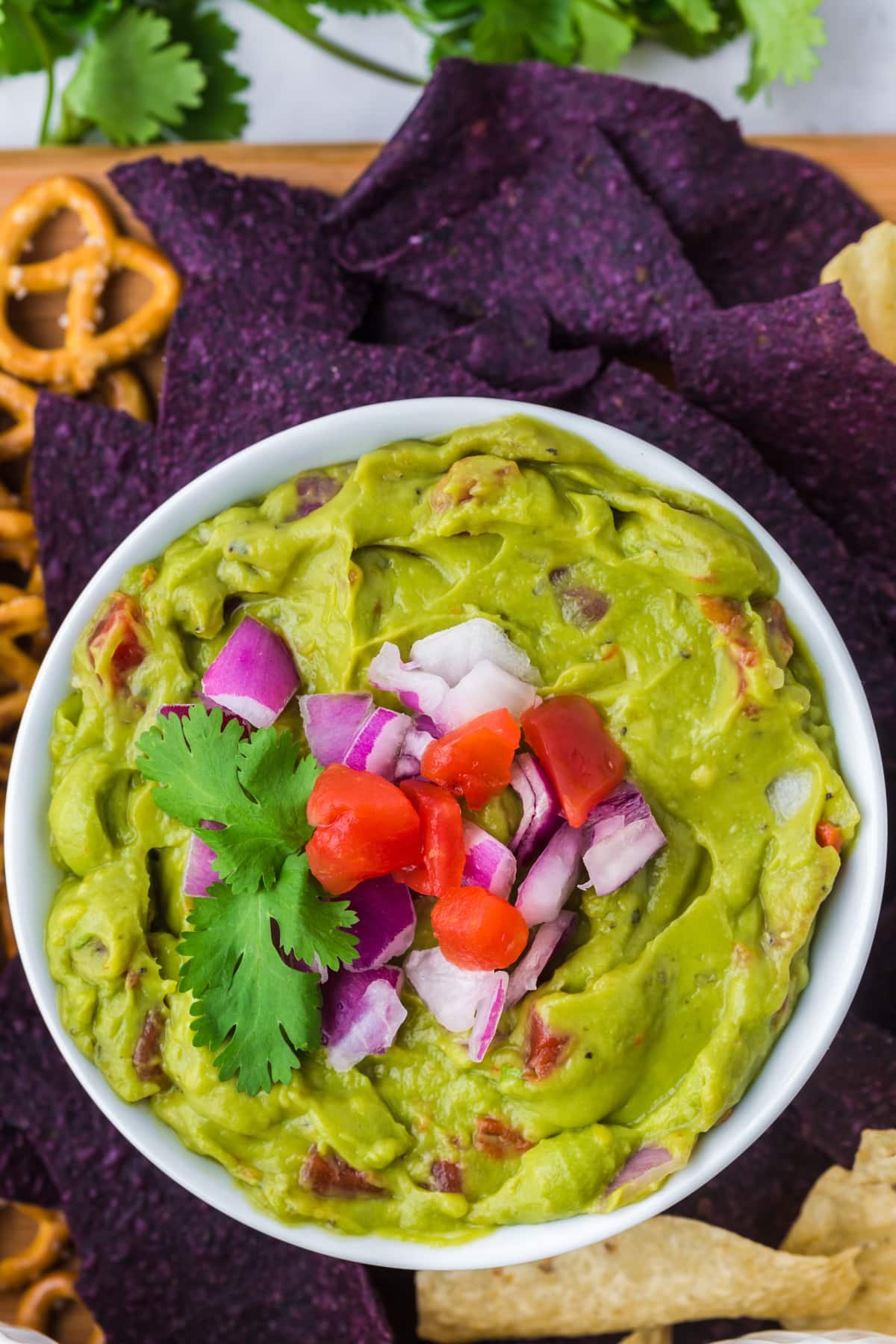 A bowl of guacamole topped with chopped tomato and red onion.