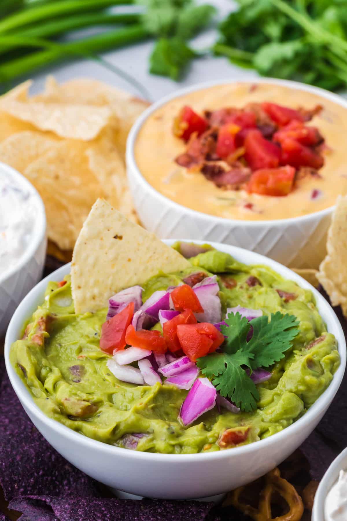 A bowl of avocado dip with a tortilla chip being dunked in.