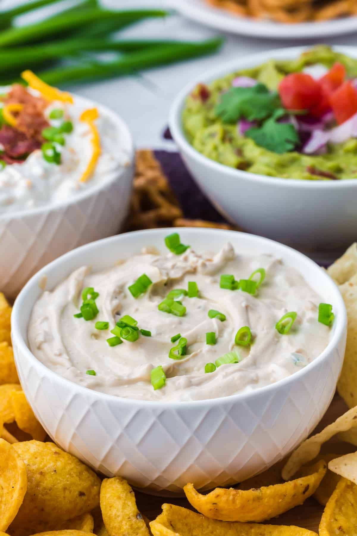 A small bowl of french onion dip garnished with green onions.