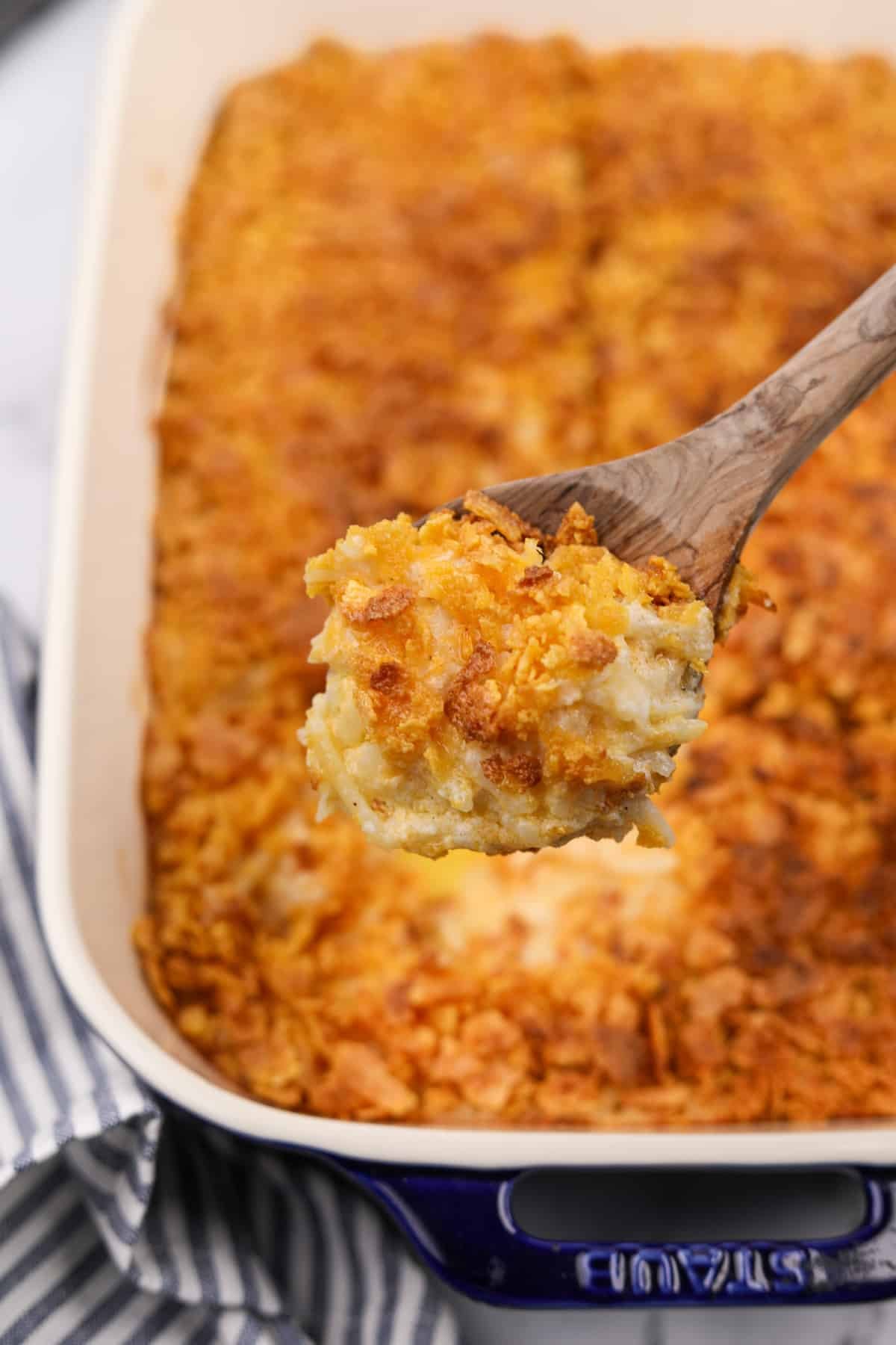 A scoop of hash brown casserole from a baking dish.