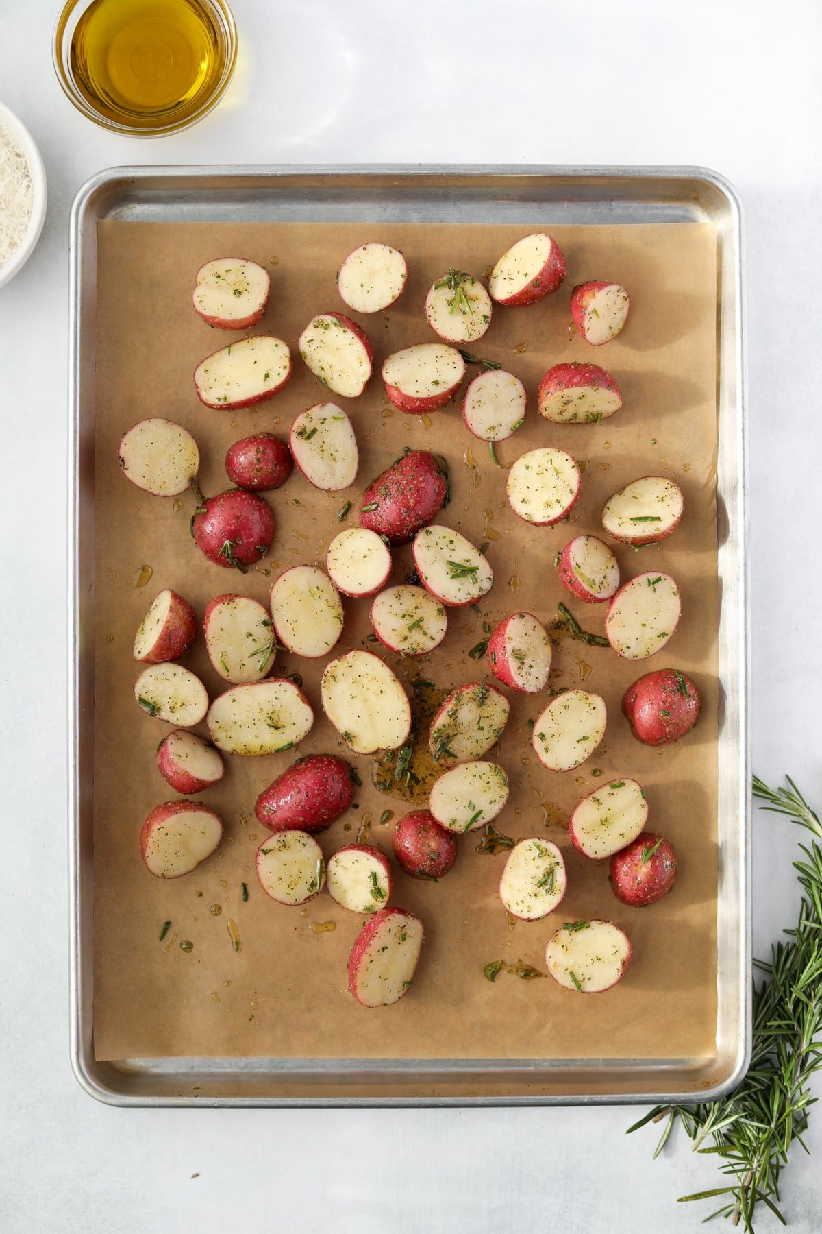 A sheet pan with potato halves spread out on a piece of parchment.