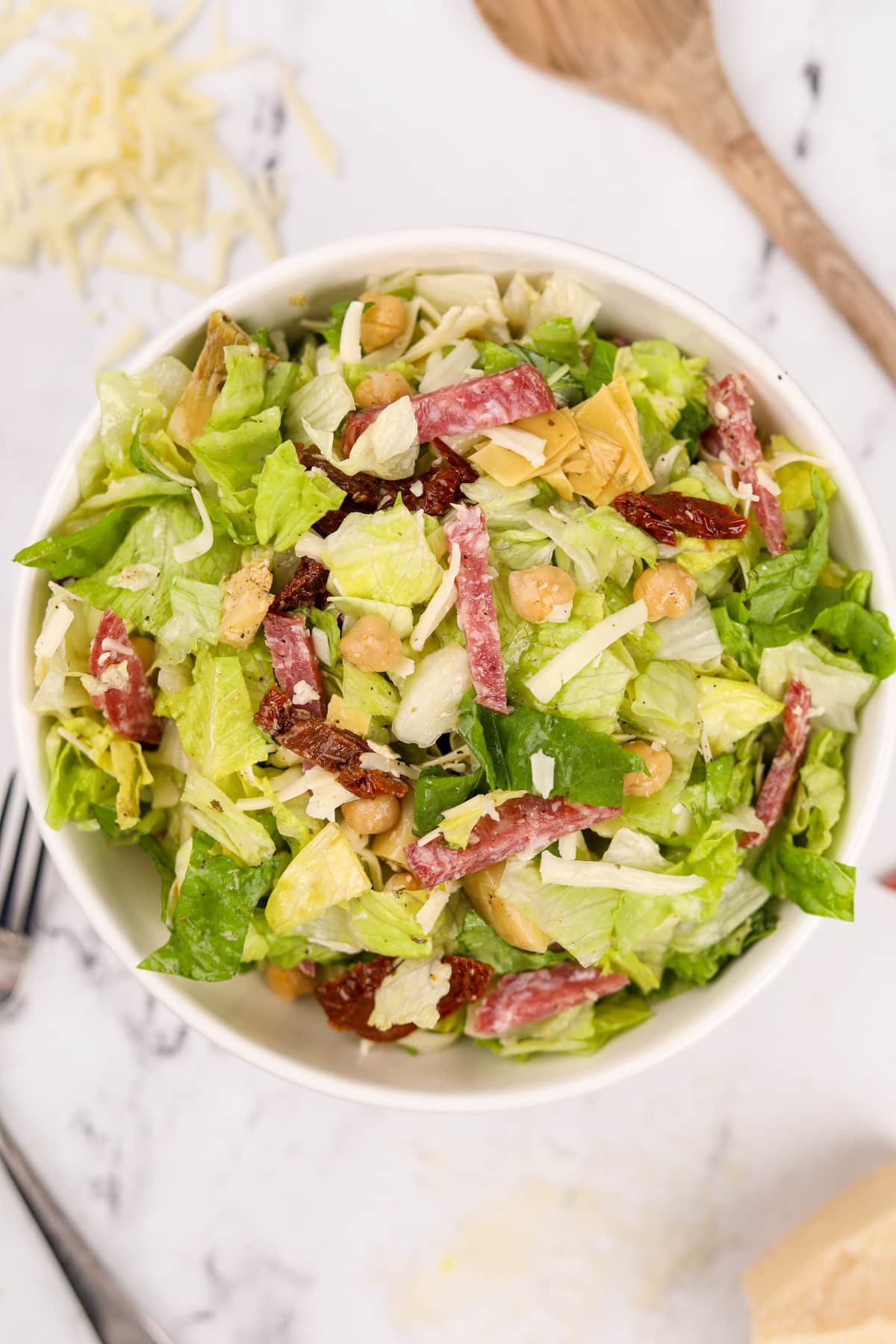 A large bowl of chopped Italian Salad with sliced salami and mozzarella.