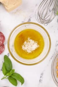 A small bowl with parmesan cheese, olive oil, and wine vinegar.