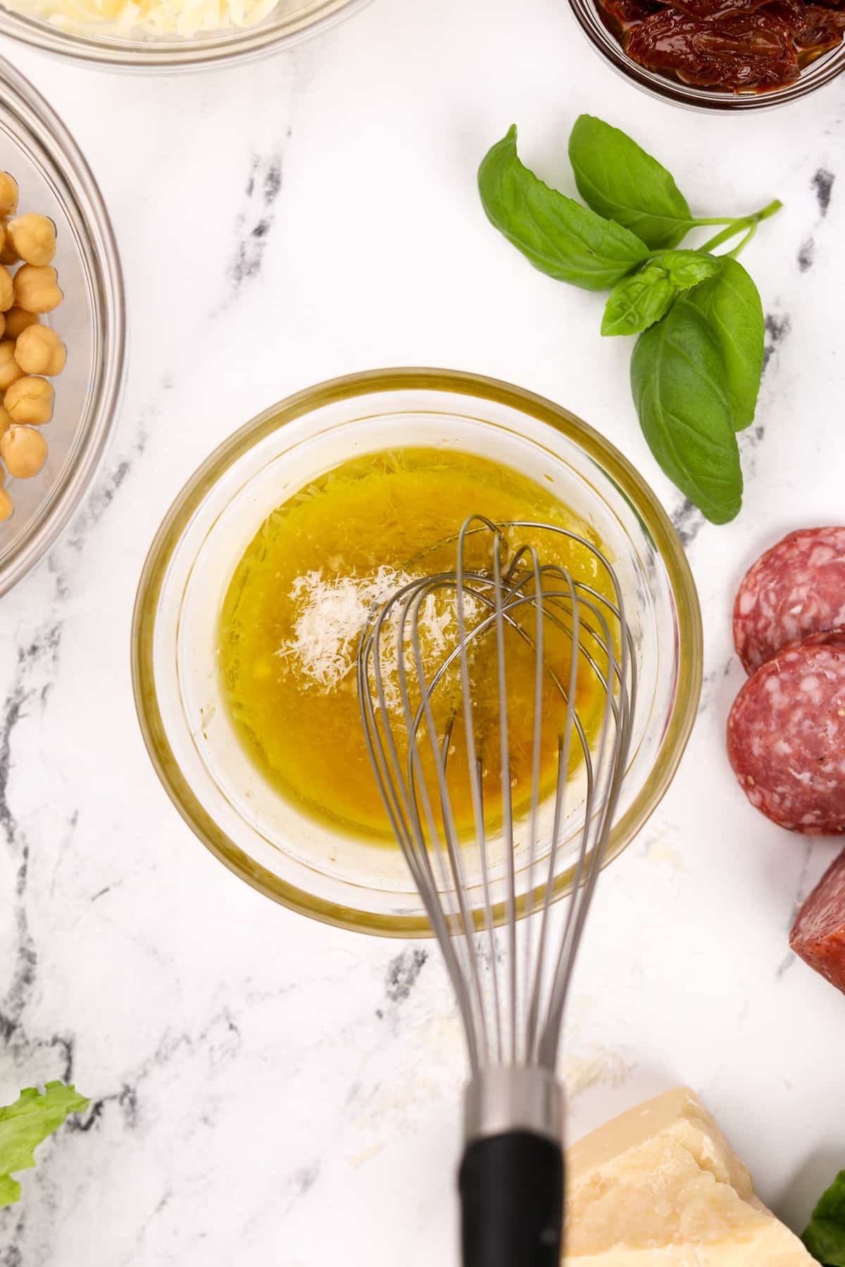 Whisking together a dressing that includes olive oil and parmesan cheese.
