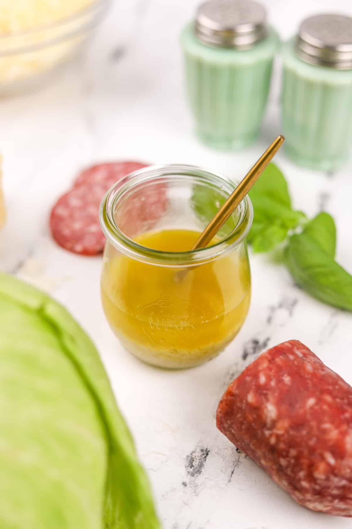 A small glass jar filled with a bright vinaigrette dressing.