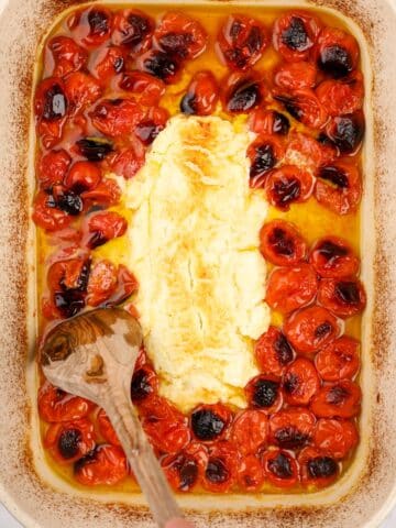 A baking dish with roasted cherry tomatoes and goat cheese.