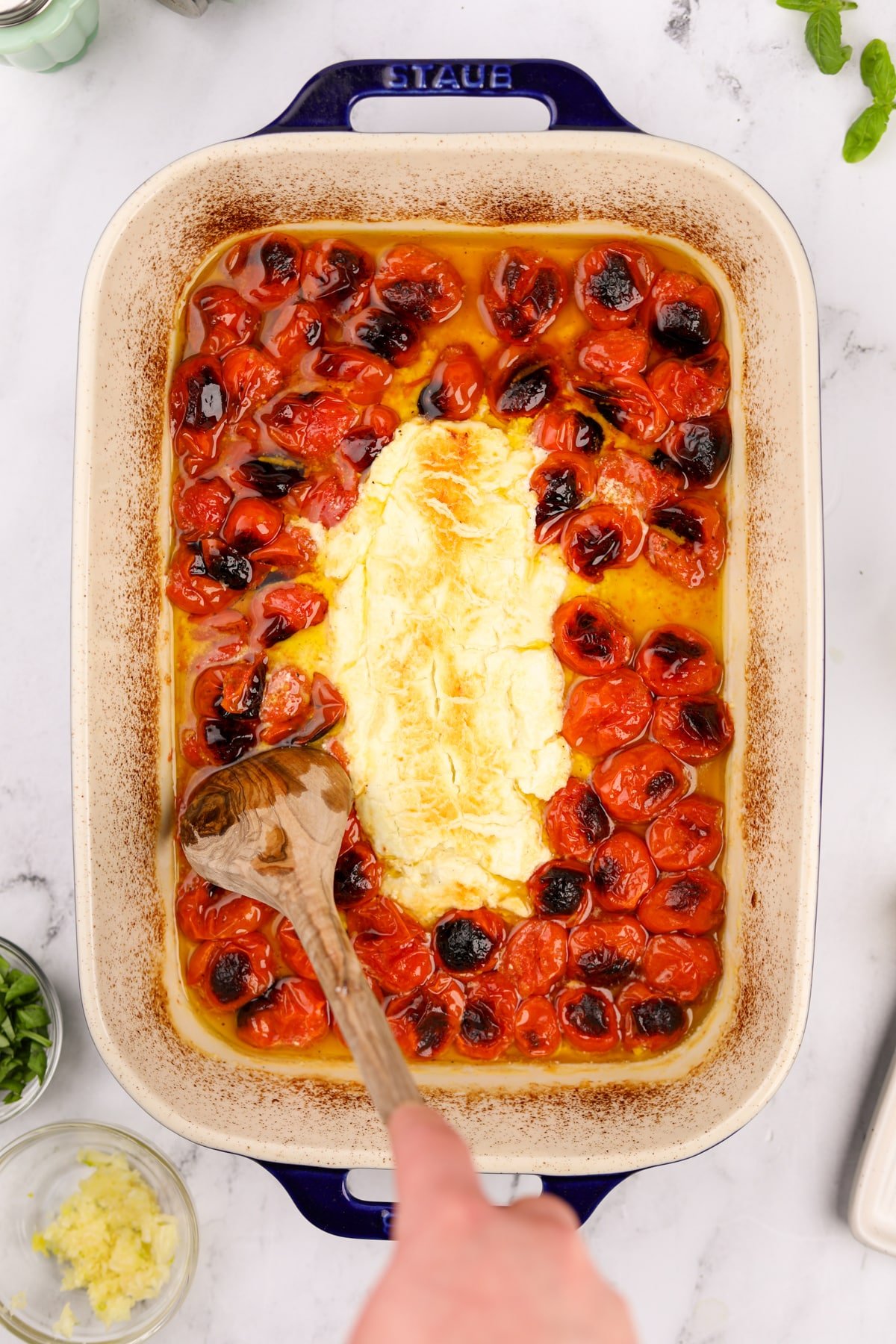 A baking dish filled with roasted cherry tomatoes and goat cheese.