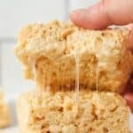A stack of three rice krispie treats, with one being pulled up, showing the gooey marshmallows.