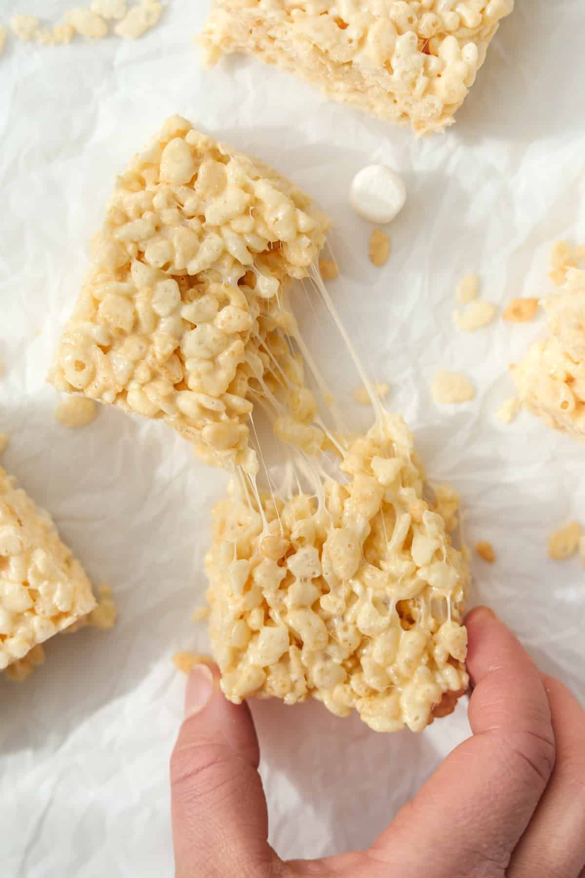 Pulling a cereal treat apart to show the gooey marshmallow.
