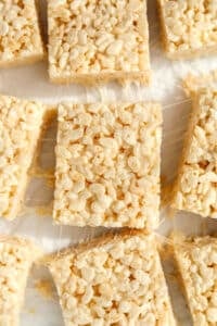 Cereal treats that have been sliced on a sheet of white parchment paper.
