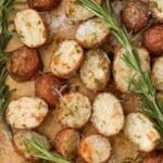 A sheet pan filled with roasted baby potatoes, garnished with fresh sprigs of rosemary.