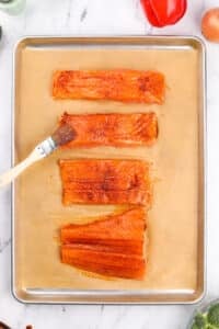 Brushing salmon fillets with a seasoned oil.