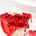 A slice of cheesecake pie topped in cherry pie filling.
