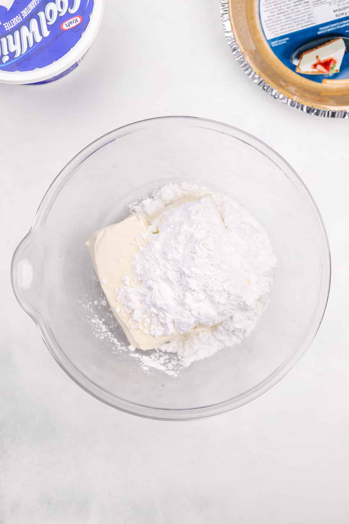 A bowl with cream cheese and powdered sugar in it.